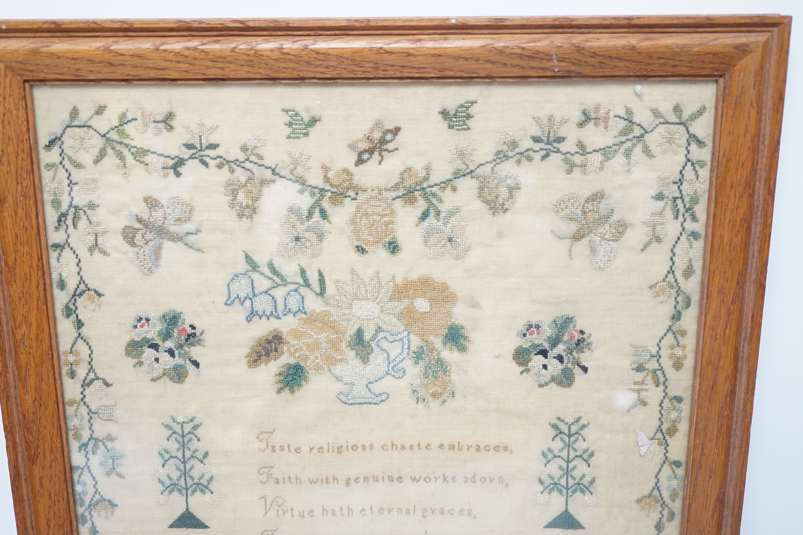 A framed sampler by Charlotte Betts, dated 1831, embroidered with a central religious verse, scrolling flowers, butterflies and birds, overall 45cm x 35cm